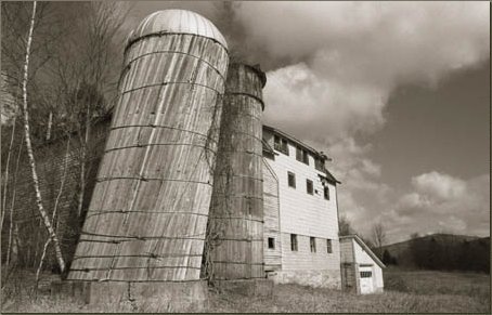 barn with leaning silos